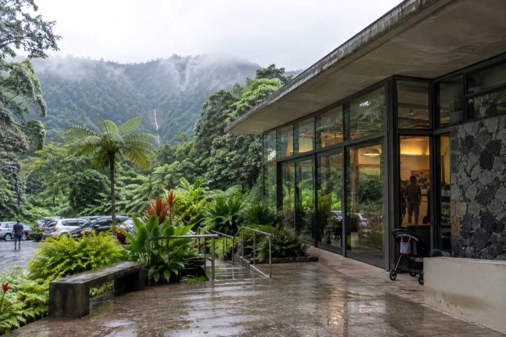 A visitor center walkway curving through tropical vegetation on a cloudy morning