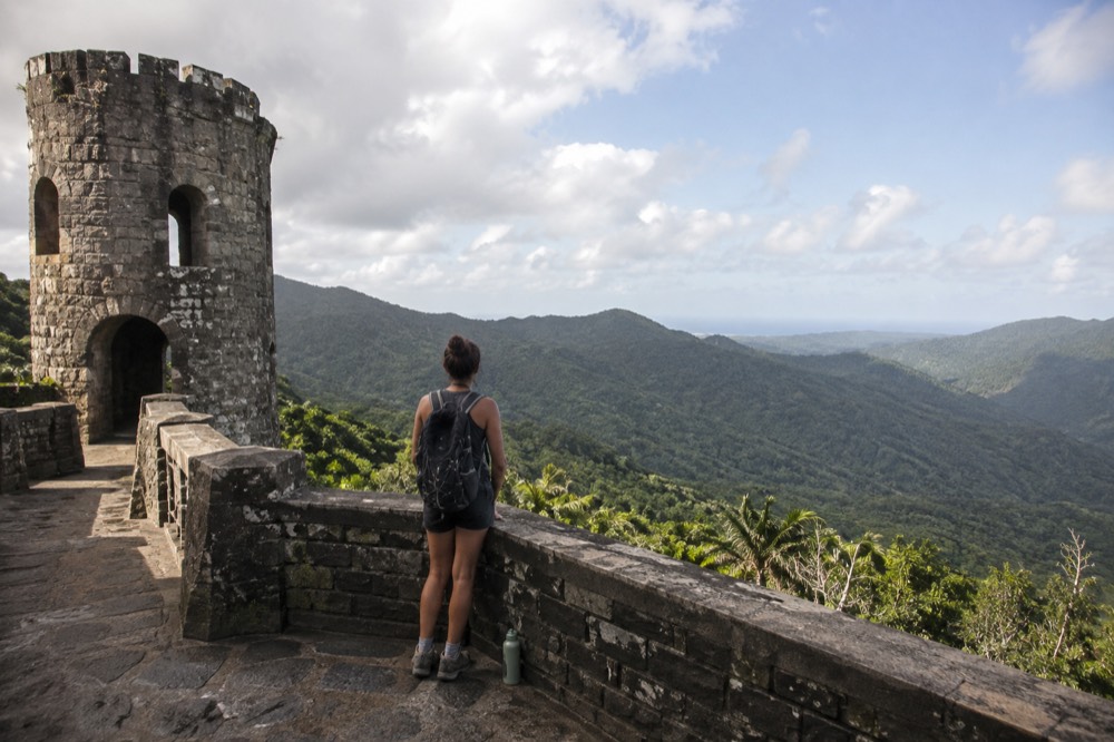 Hiker standing on a stone lookout platform above a green rainforest valley