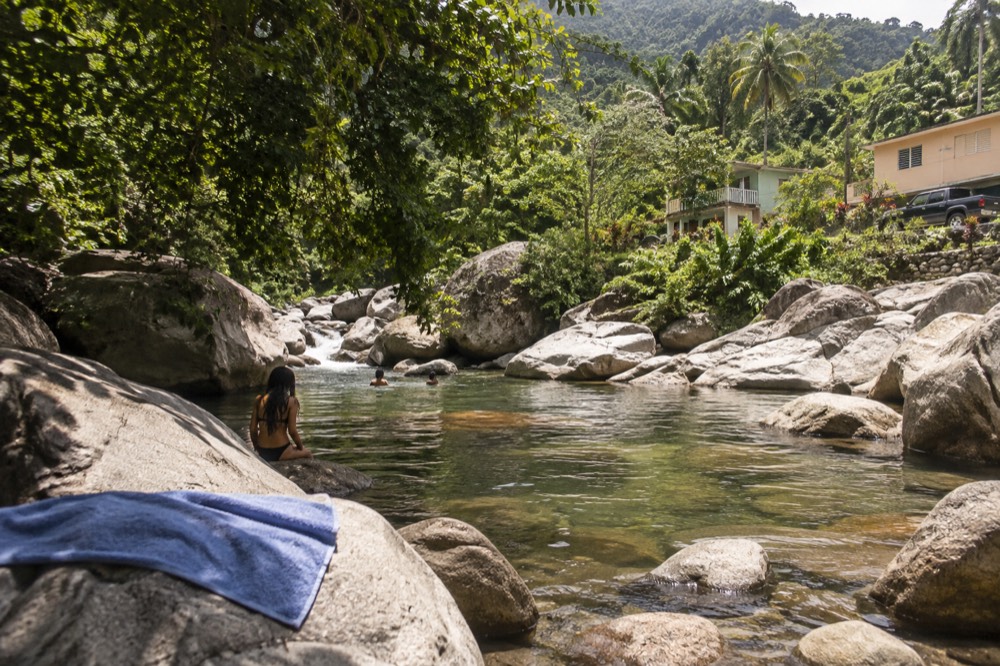 Clear shallow river pool between smooth rocks with rainforest trees overhanging the banks