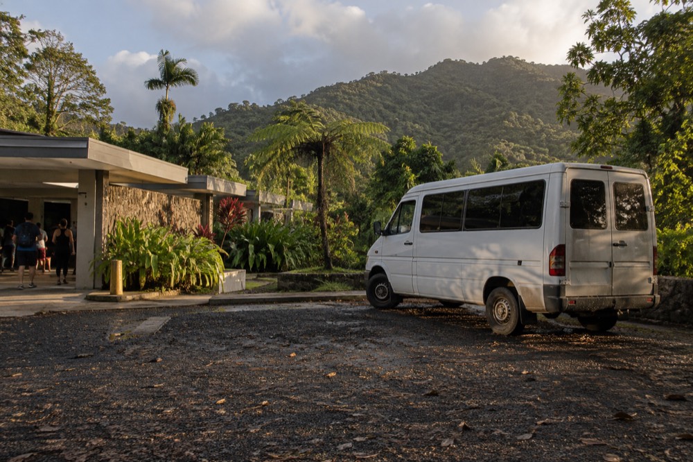 Van parked at a rainforest roadside pullout with green hills behind