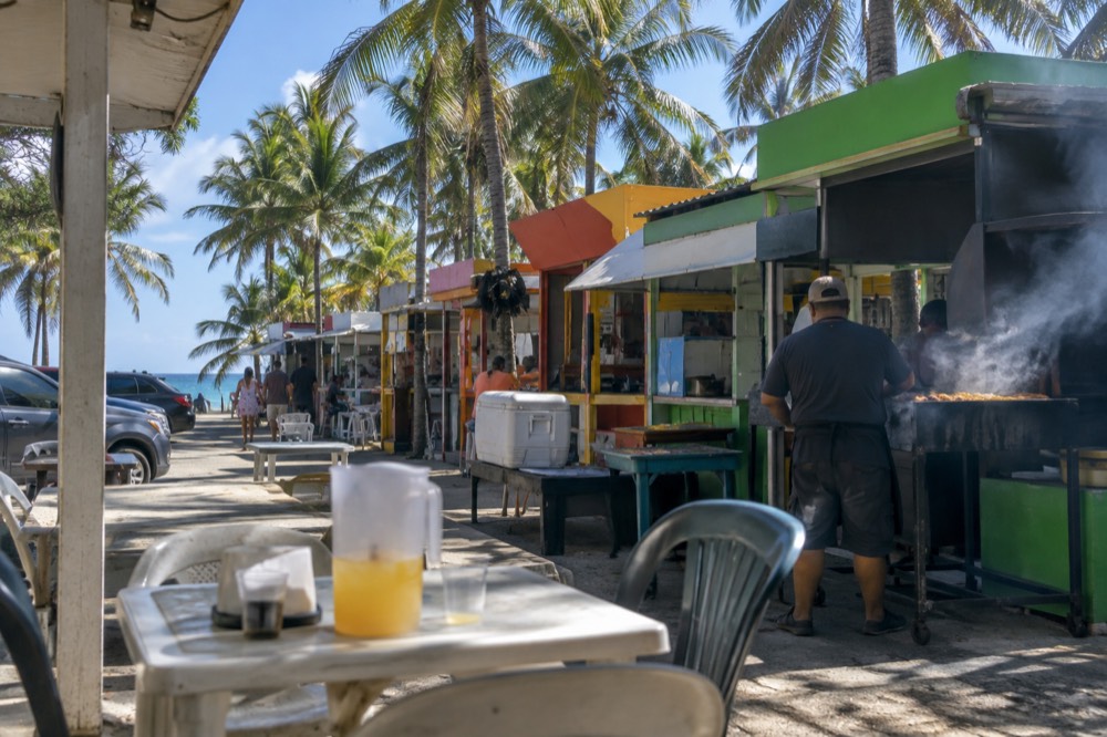 Row of colorful beachside food kiosks along a coastal road
