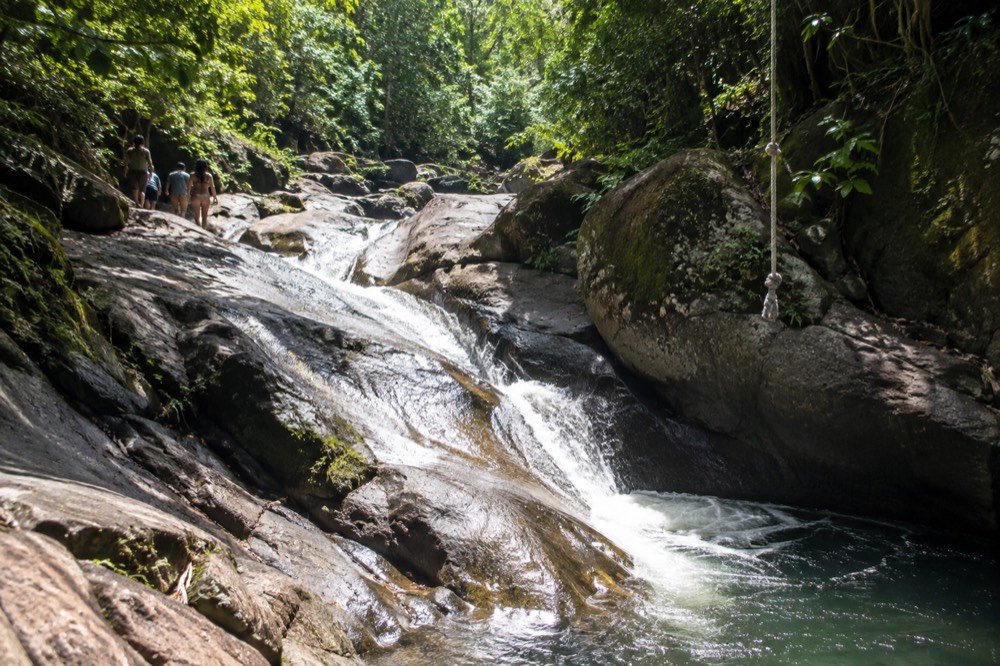 Natural rock waterslide channel with water flowing between boulders in tropical forest